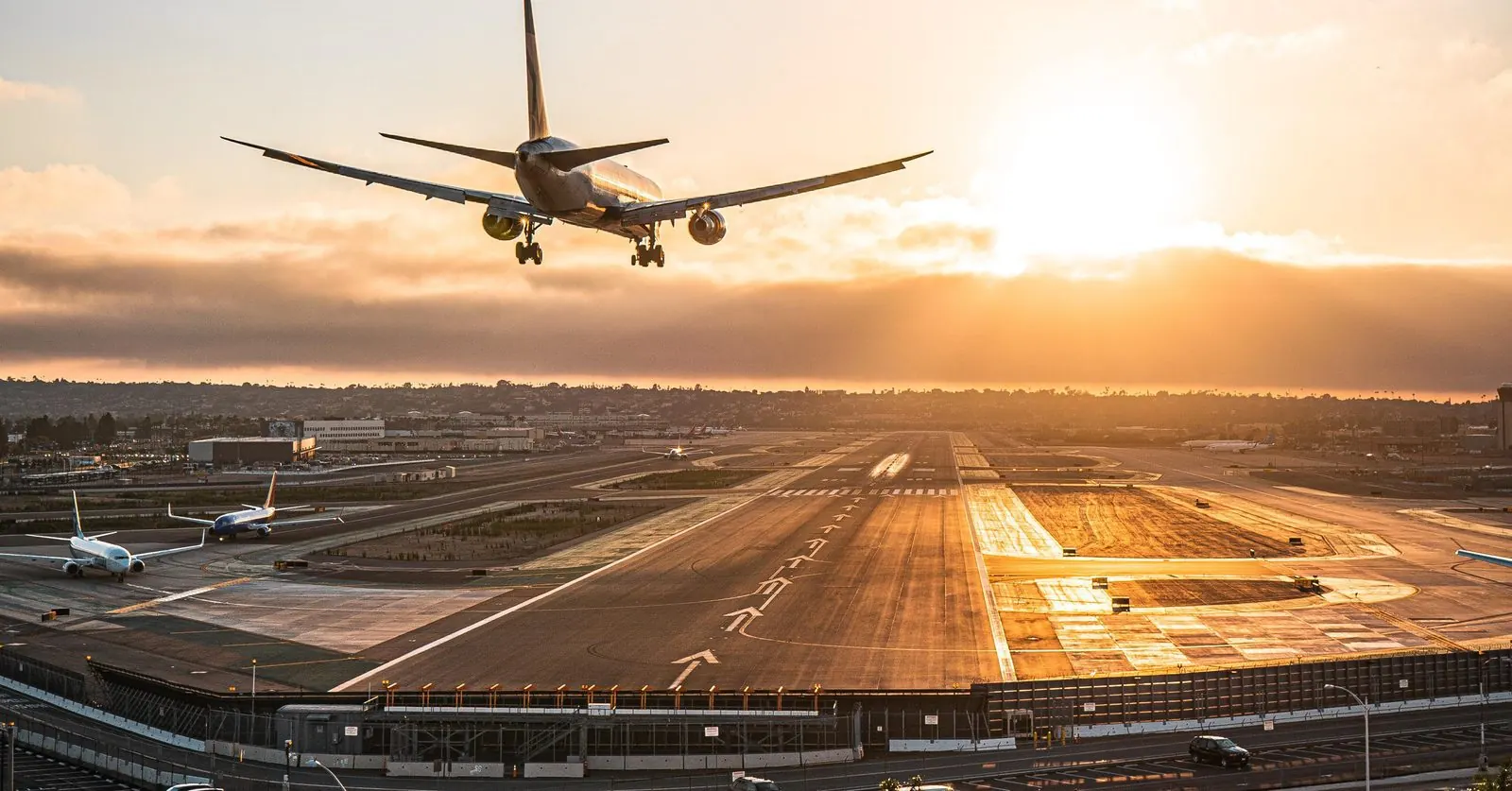 How to Avoid Back Pain While Traveling: A Chiropractor's Guide | Sports Chiropractor San Diego Airplane landing at San Diego International Airport at sunset, seen from above the runway